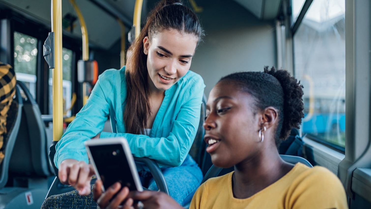 Friends using a smartphone together on a bus.