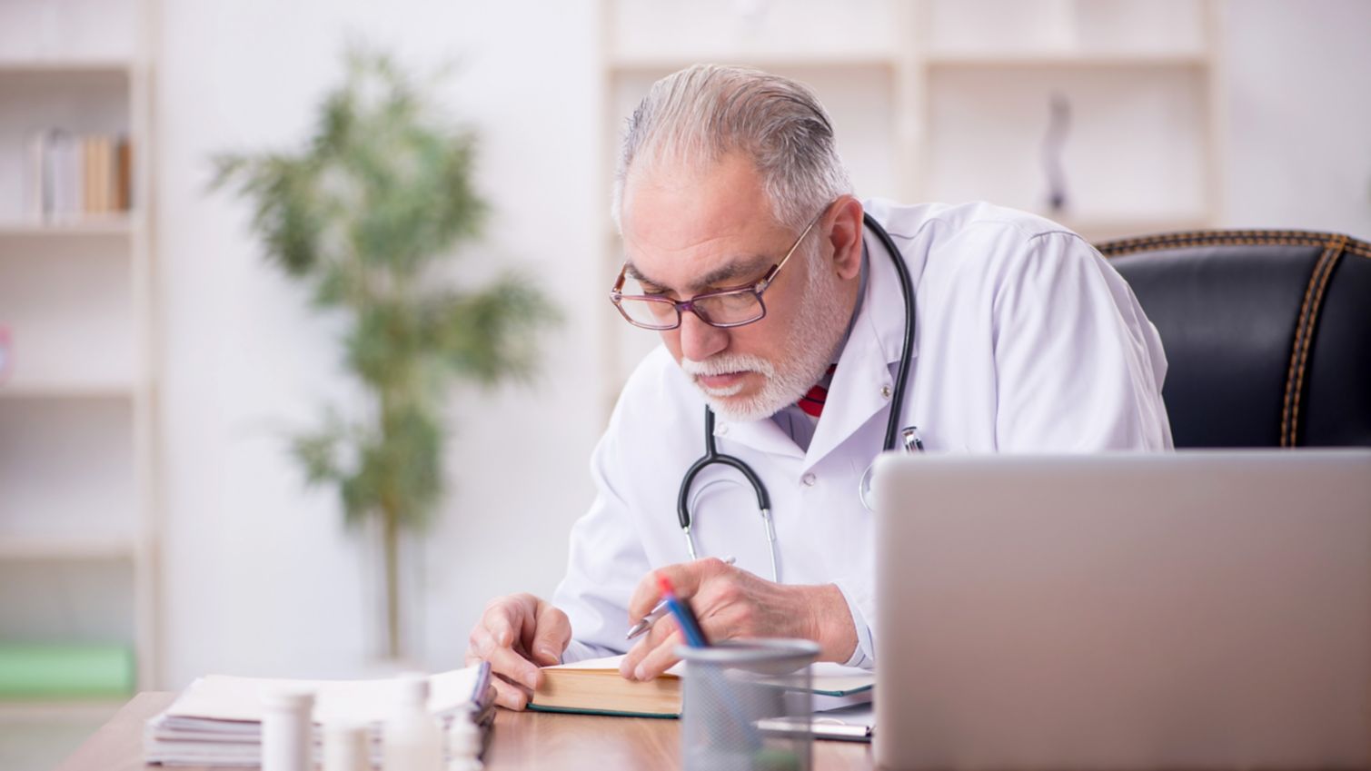 Male provider reading a medical textbook at his deck.
