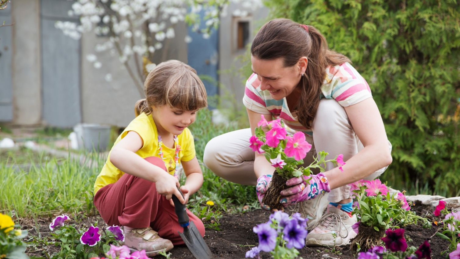 An adult and child planting flowers