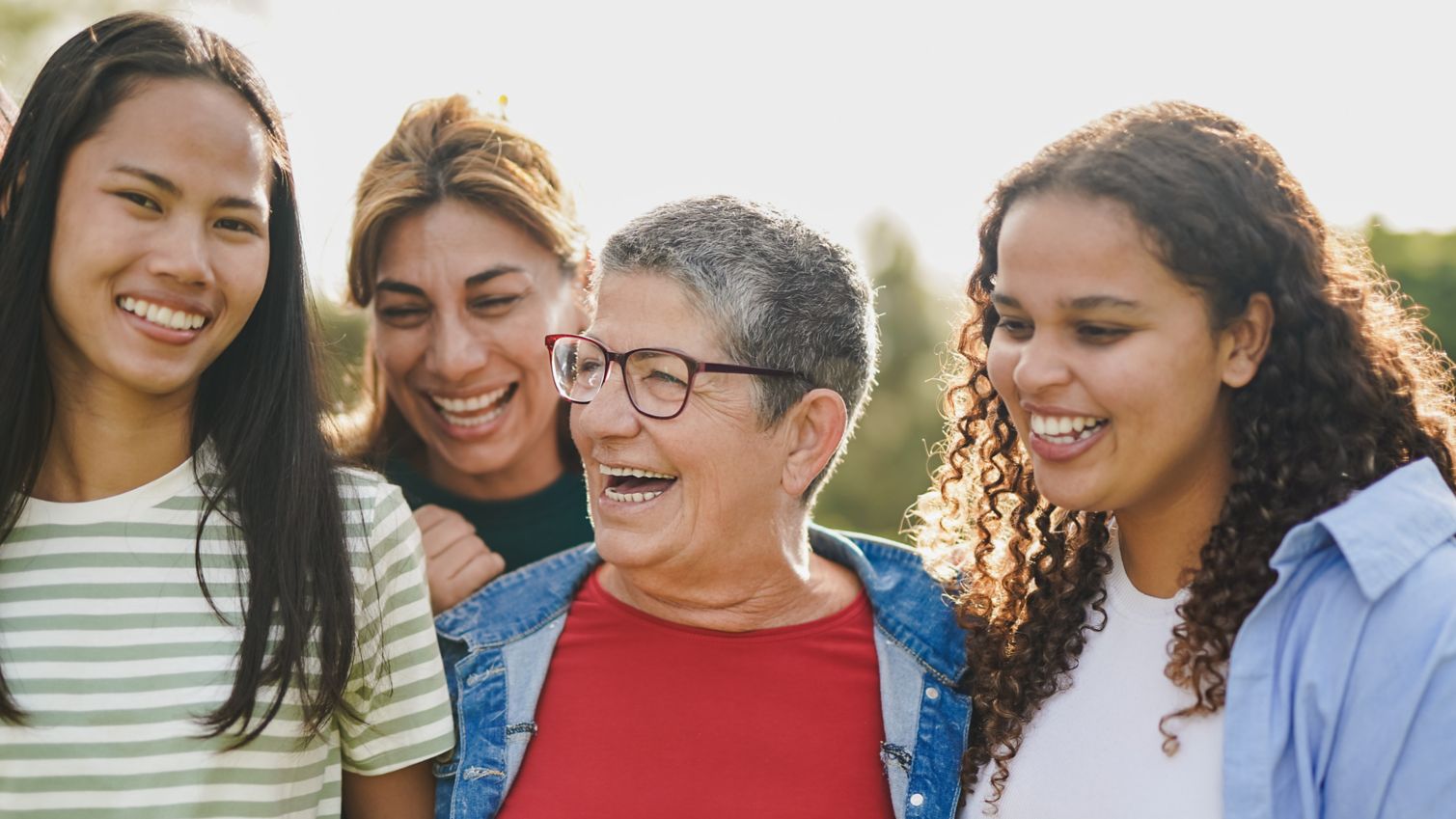 A woman smiles while surrounded by her daughter and grandchildren. 