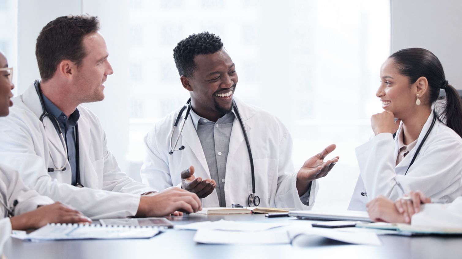 A group of 5 doctors talking  and smiling