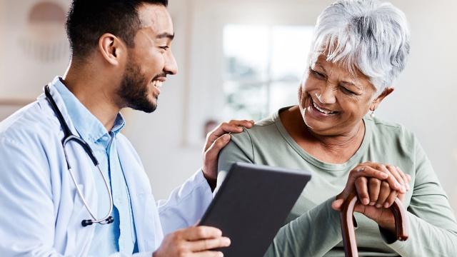 A woman smiles as her provider reviews her chart. 