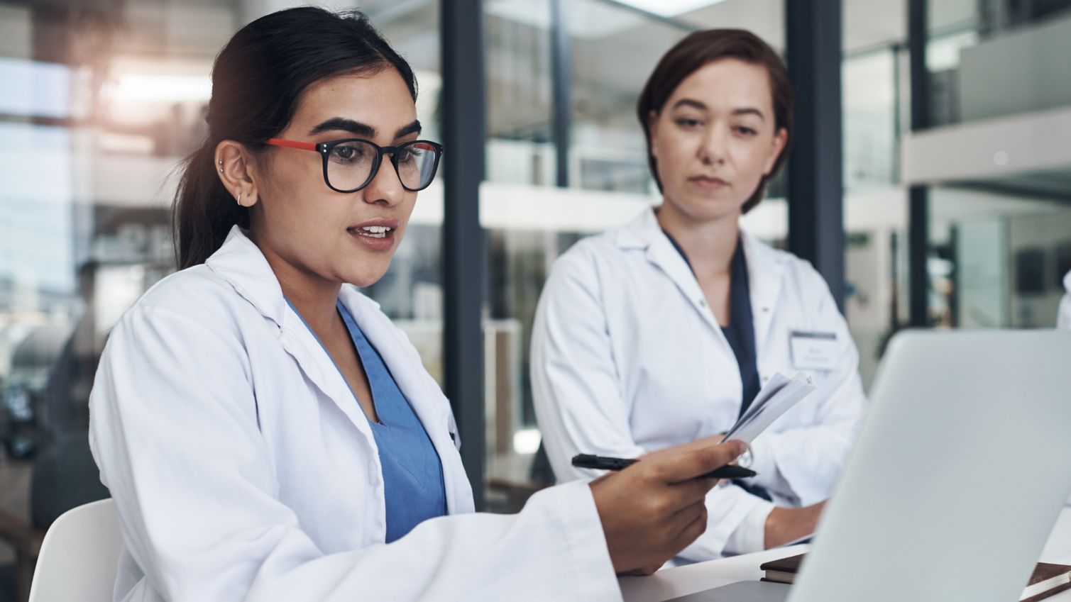 Two female providers reading notes and looking at a computer.