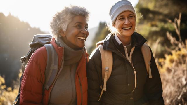 Two women smile while hiking together. 