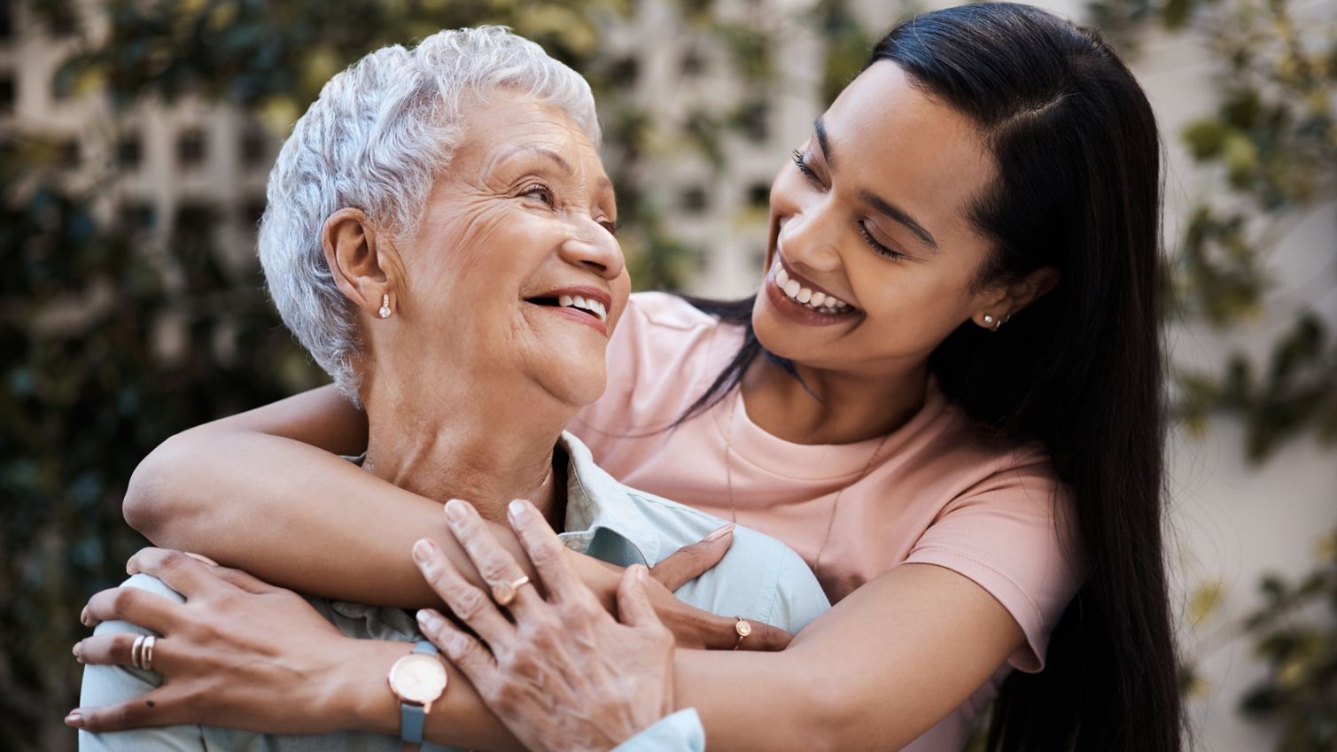 A daughter hugs her mother while smiling to each other. 