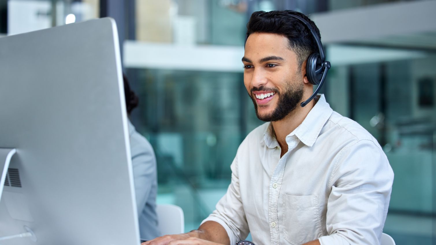 Man at call center and web support communication at a computer in a office. Phone conversation, smile and male worker with contact us, crm and customer service job in a consulting agency