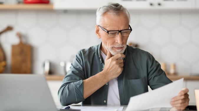 A man reviews documents while at his computer. 