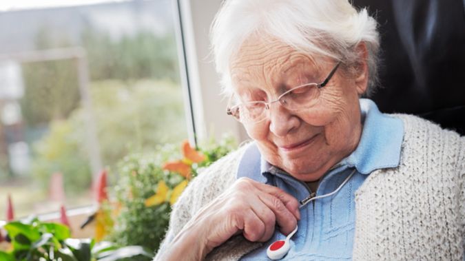 A woman looks down at her medical alert device. 