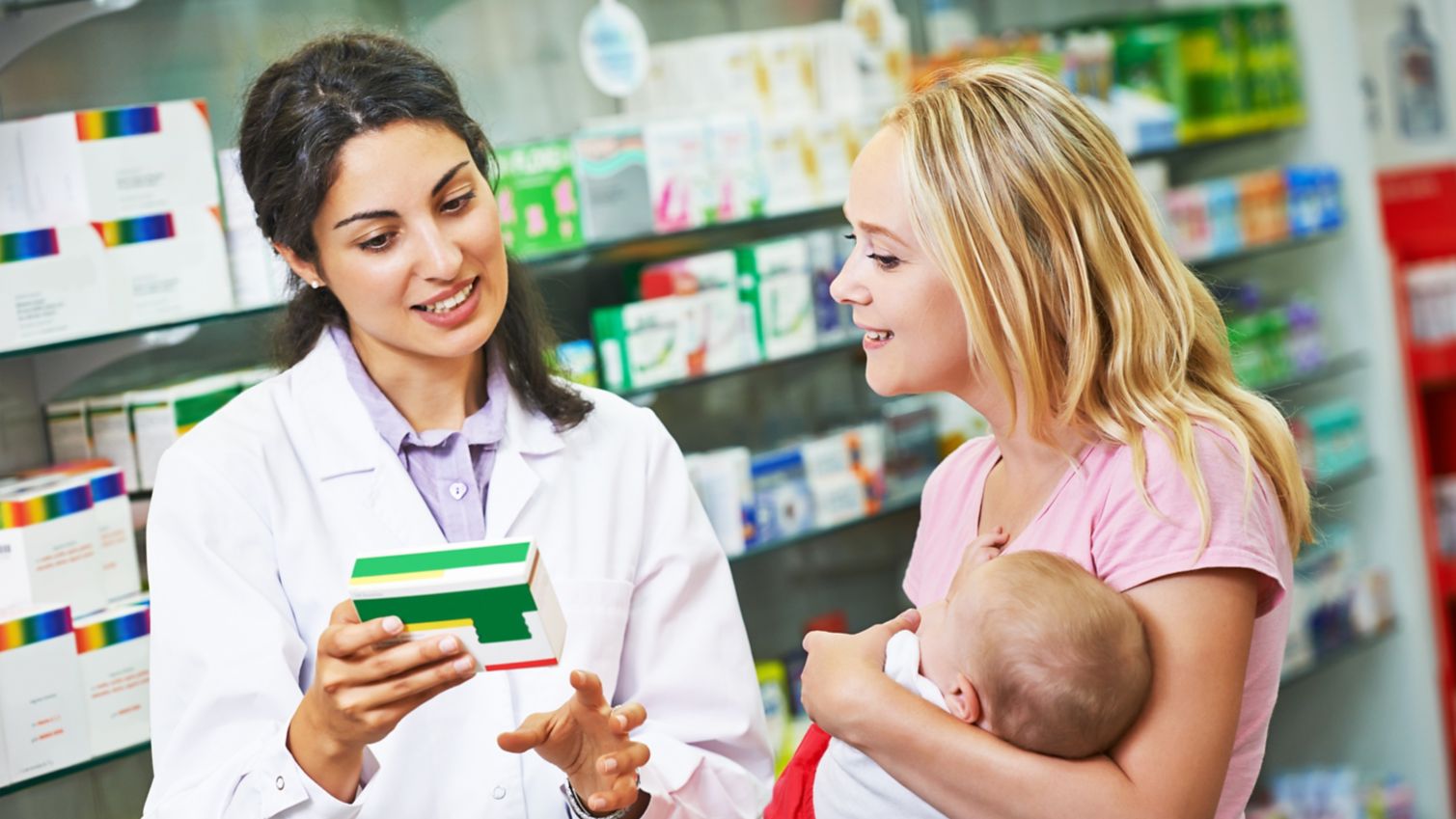 Pharmacist giving vitamins to mother with child in drugstore