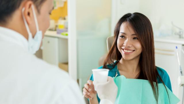 Dentist handing a patient a cup of water