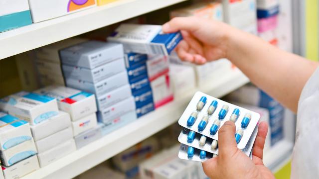 Person stocks medication on shelf.