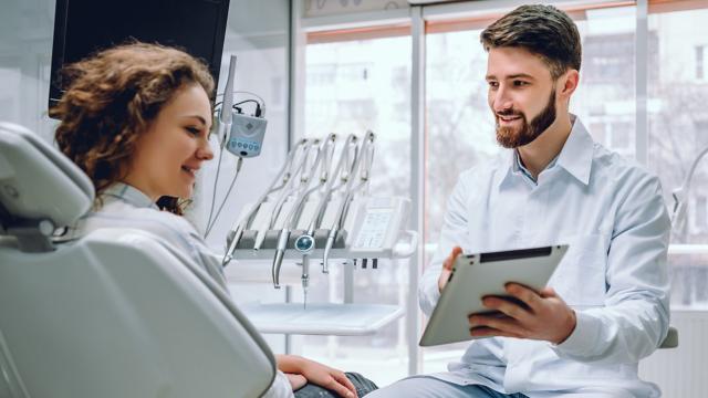 Dentist shares his tablet screen during discussion with patient.