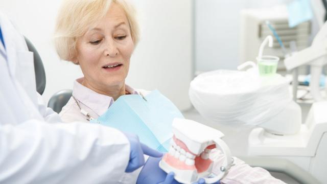 Woman in dentist chair talks with her dentist.