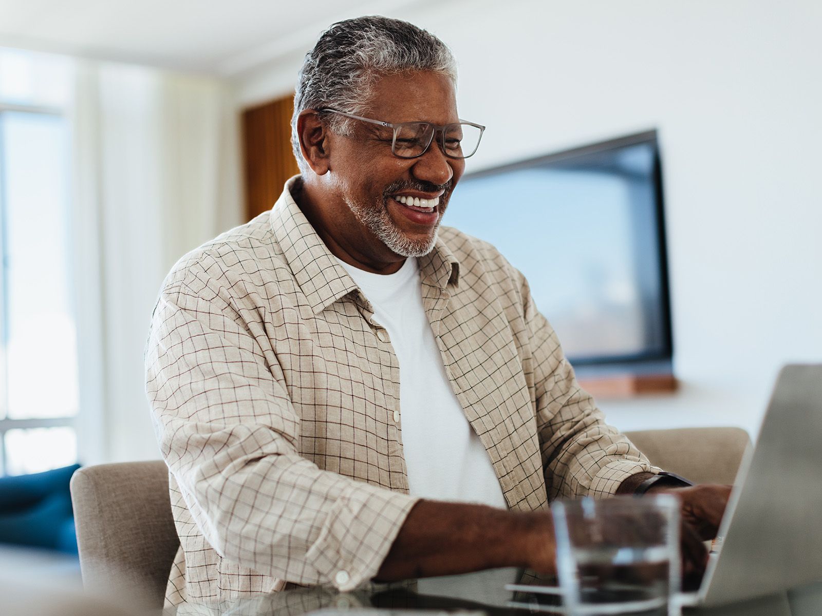 A smiling senior man uses his laptop at home.