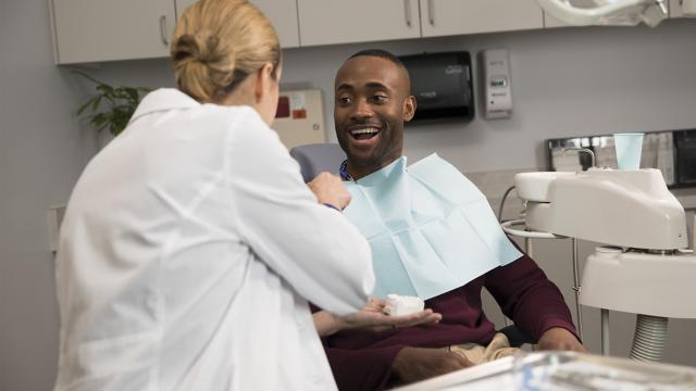 Dentist speaking to patient in chair.