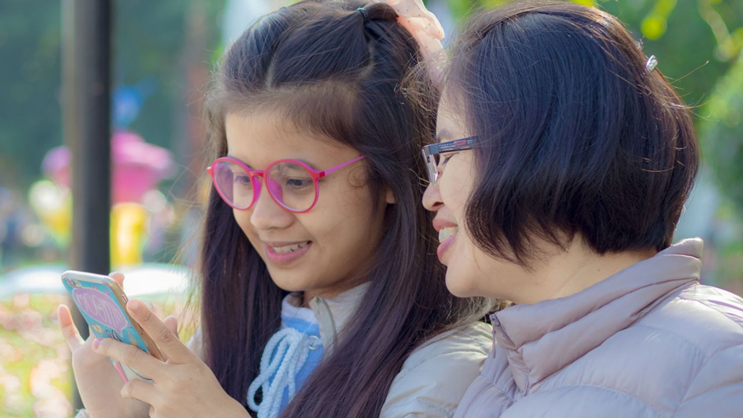 A grandmother and granddaughter reading in the park.