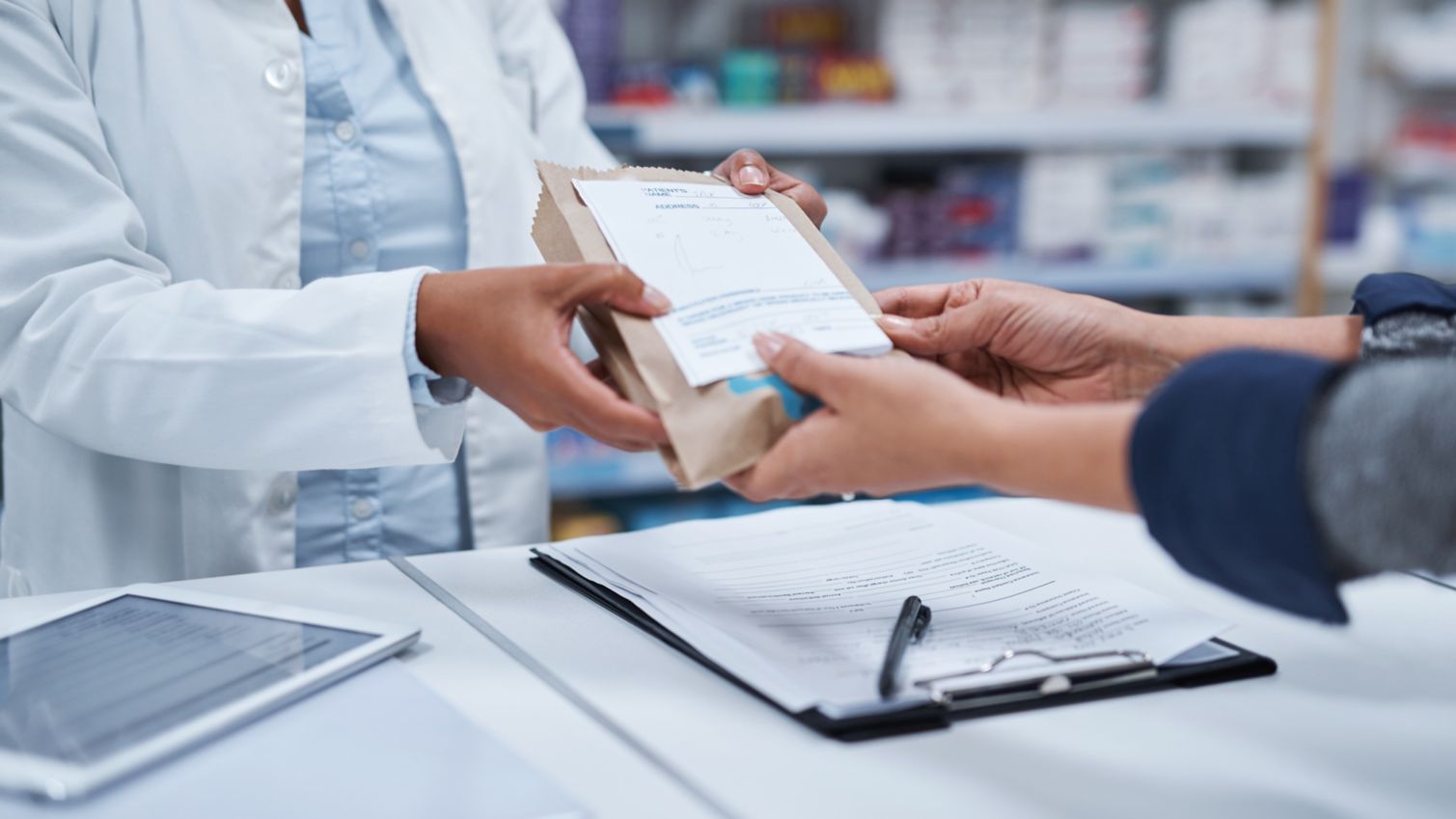 A pharmacist hands a woman her prescription drugs in a bag