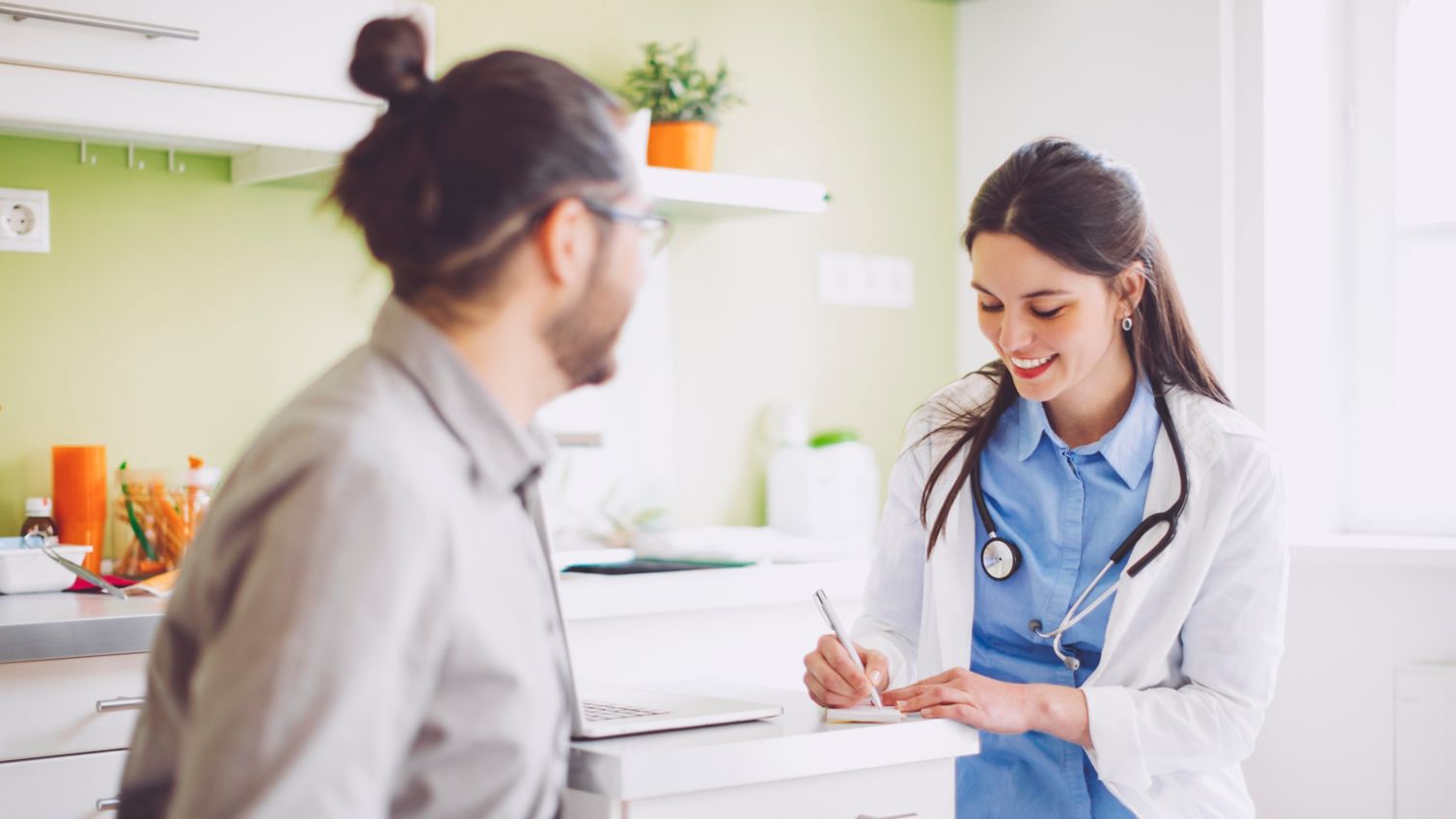 A female physician writes a prescription for a male patient