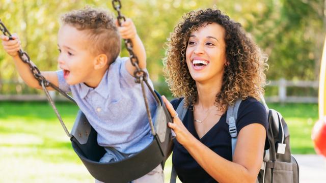 Mom pushing son on swing