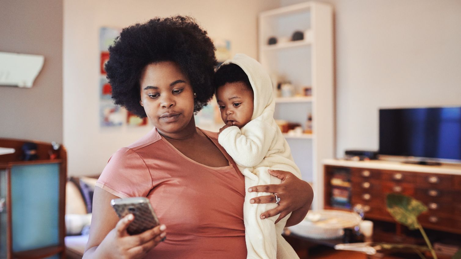 Mom holds infant while reading news on her cellphone