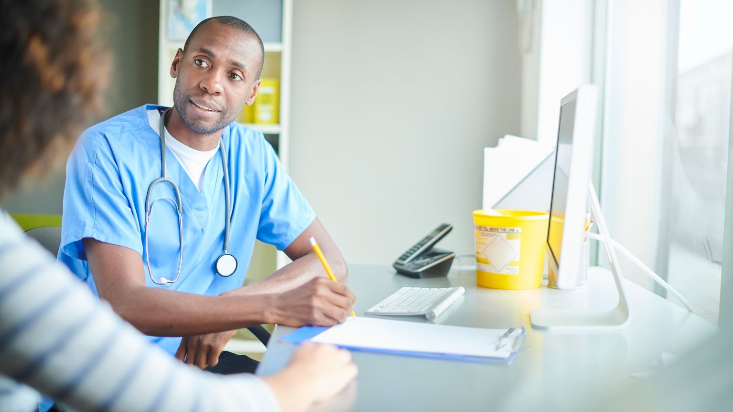 A male doctor takes notes on a patient's chart