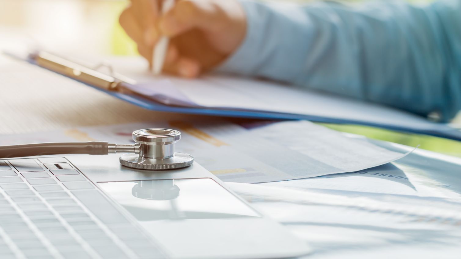 A healthcare professional takes notes on a patient's chart