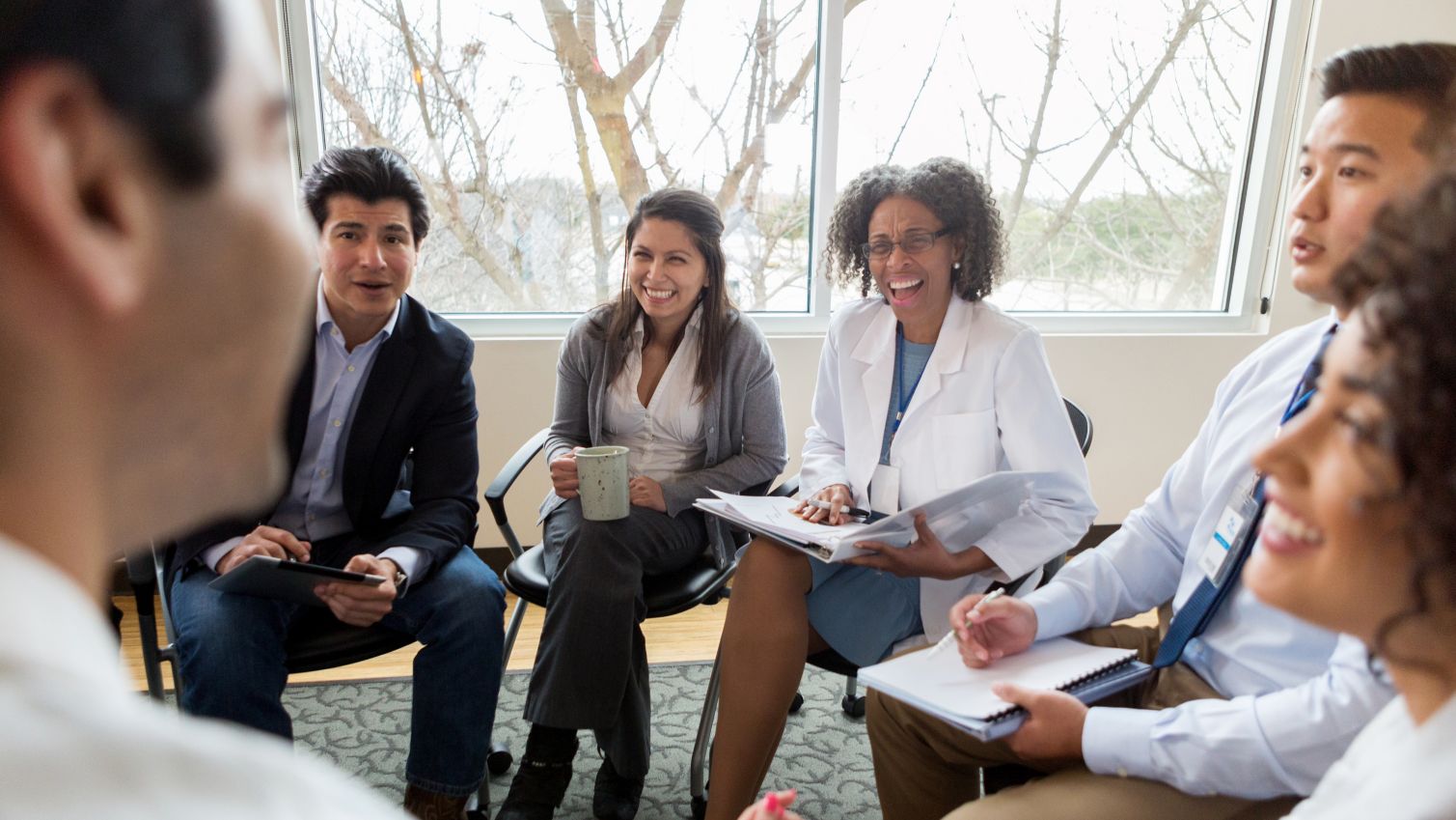 A group of physicians smile and laugh while having a meeting