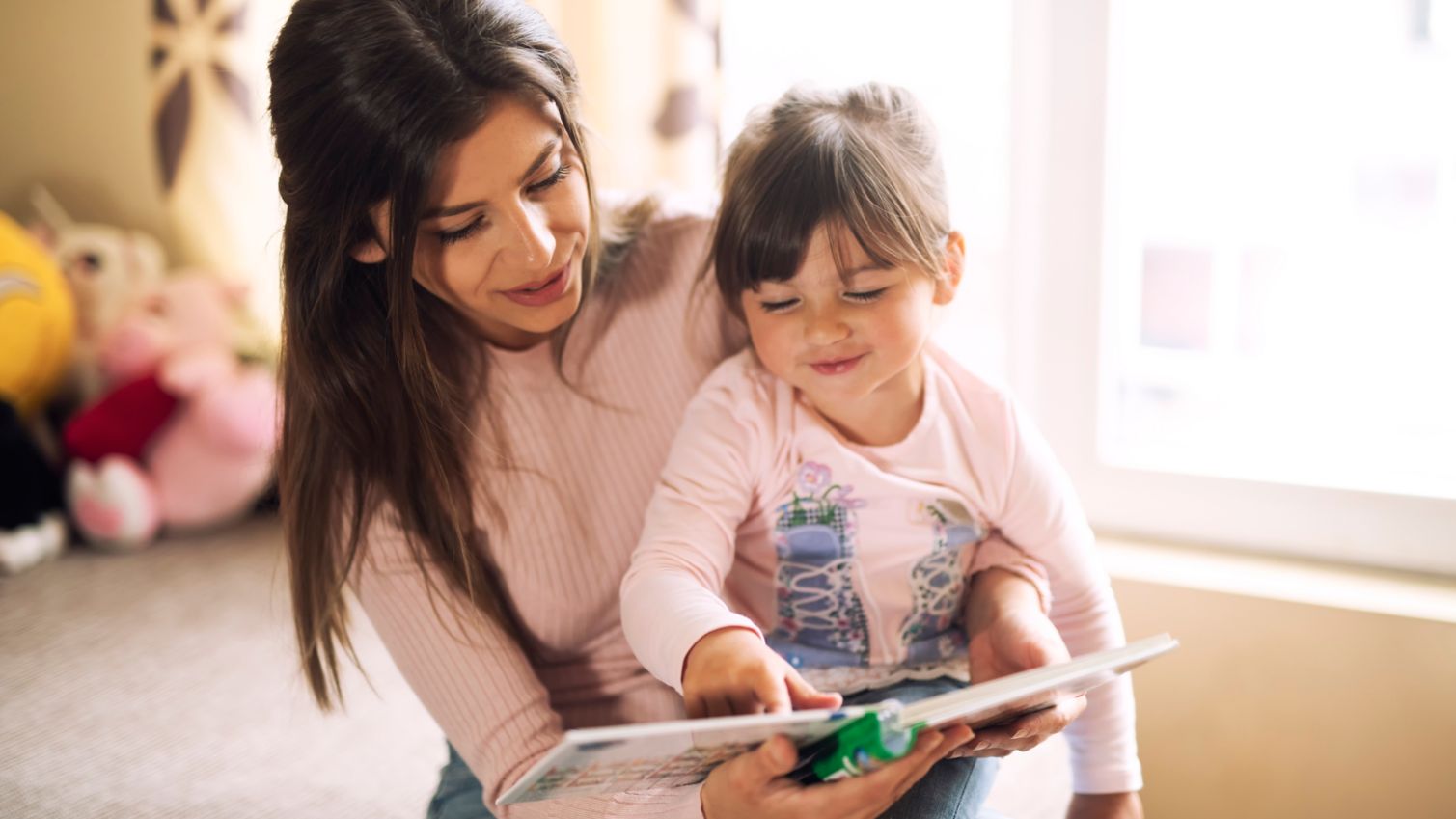 Mom holds daughter while reading a book