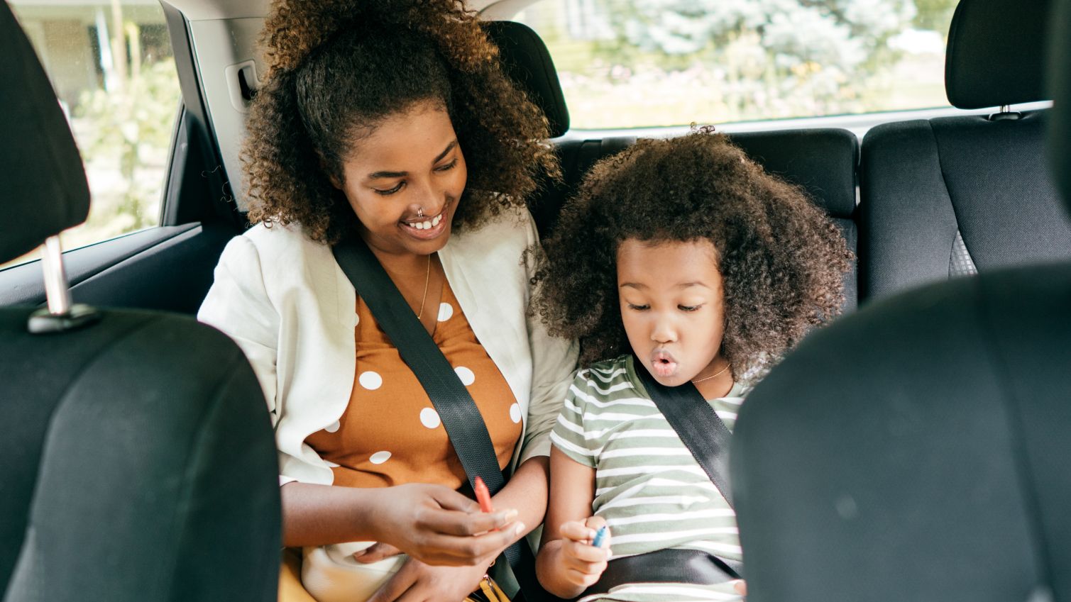 Mom and daughter travel in back seat of car