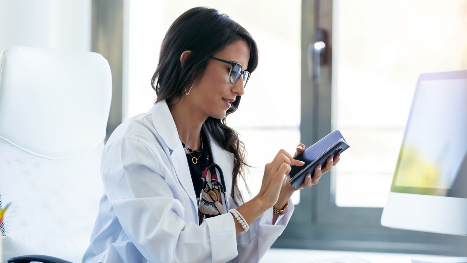 A female physician reads information on her phone while at work