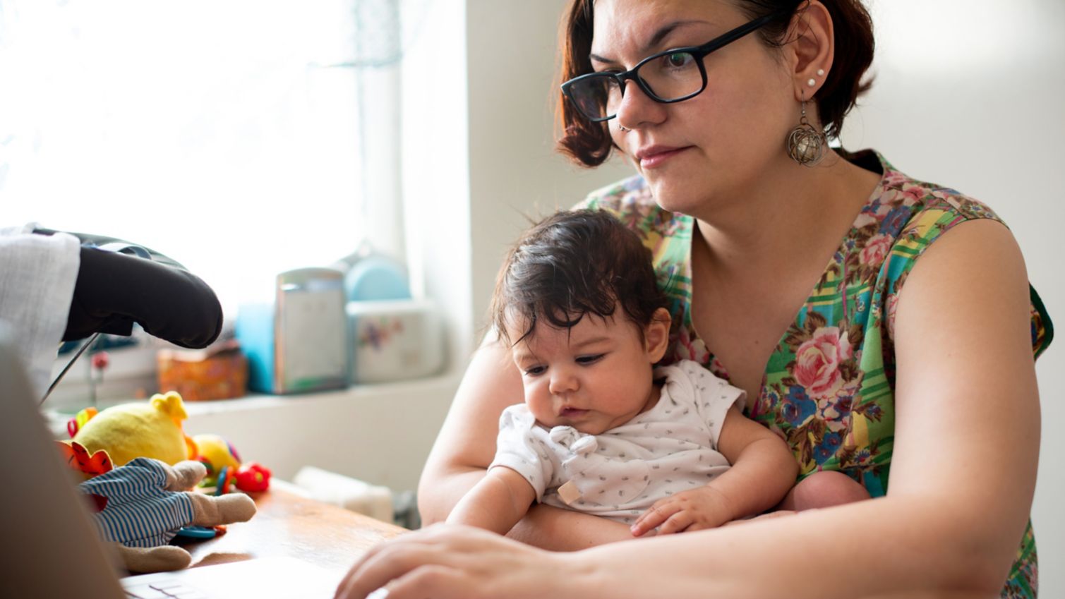 Mother with baby on lap looking at laptop