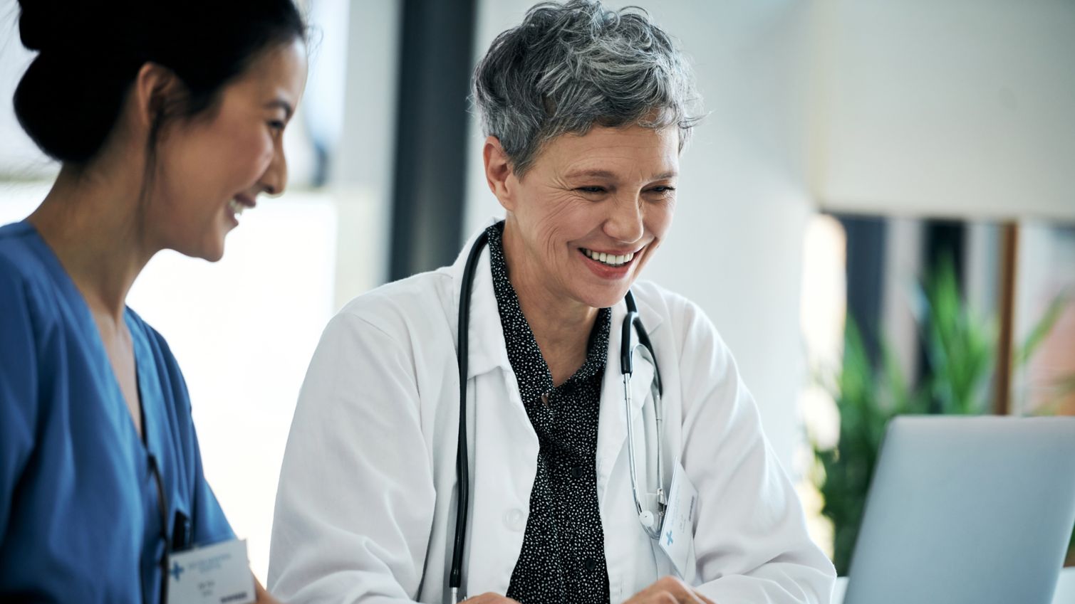 Two female healthcare workers research information on a laptop
