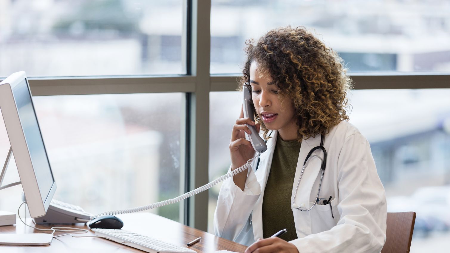 A female physician talks on a phone at her desk