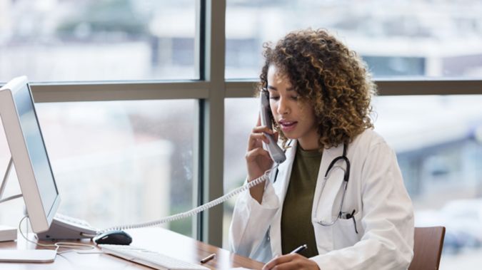 A female physician talks on a phone at her desk