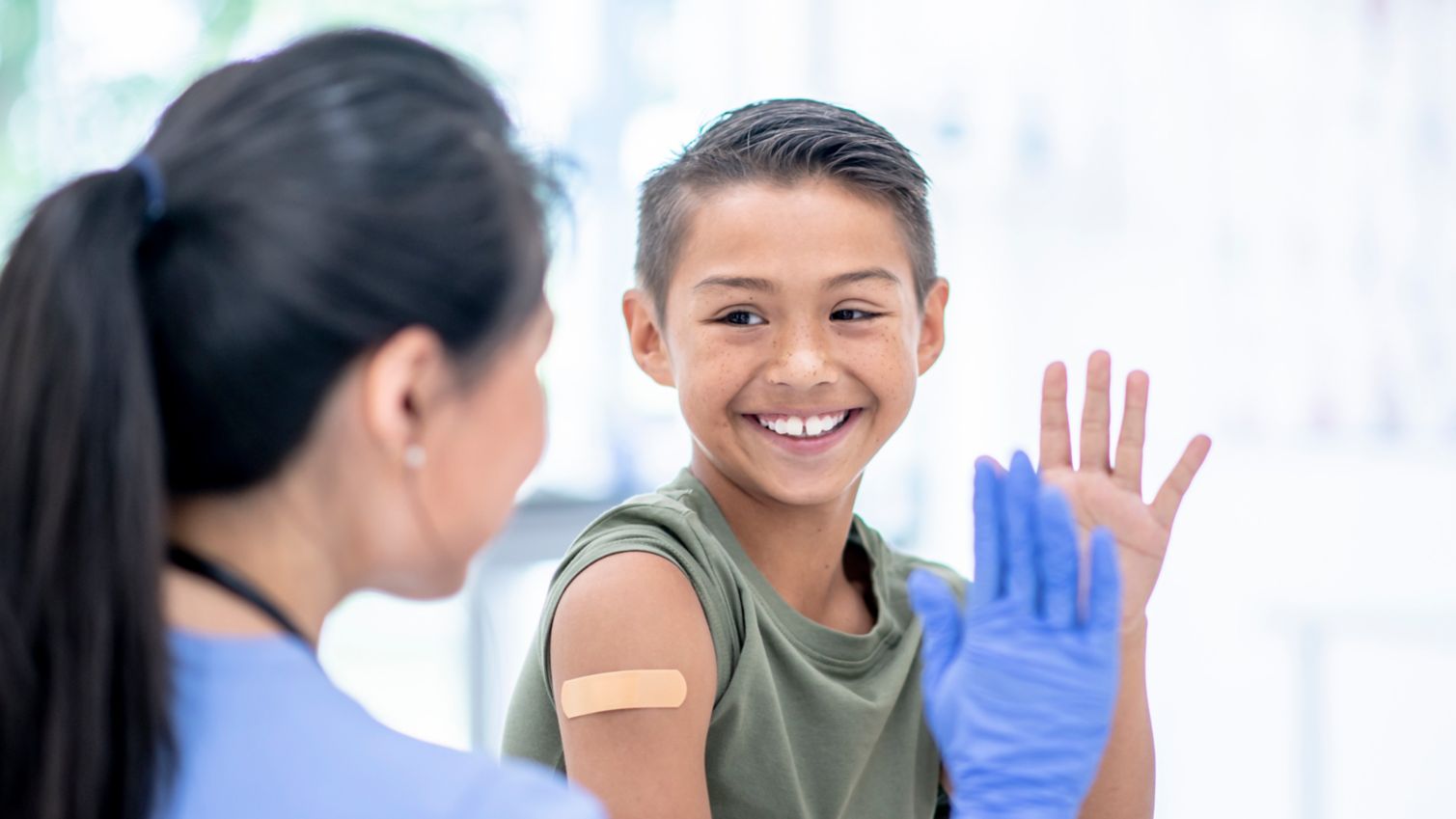 Doctor high-fives young patient after vaccination