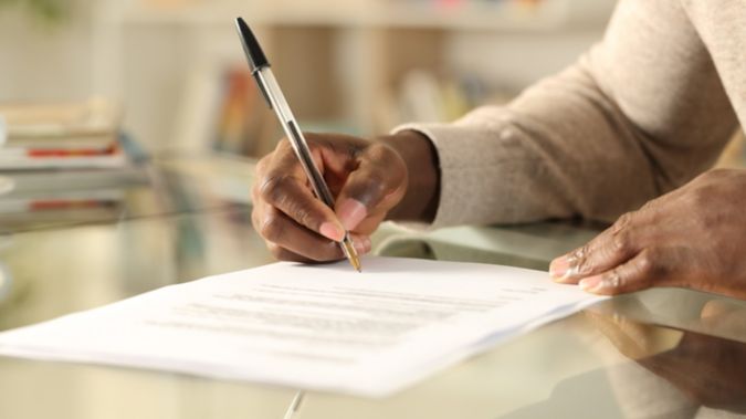 A woman filling out paperwork on her desk