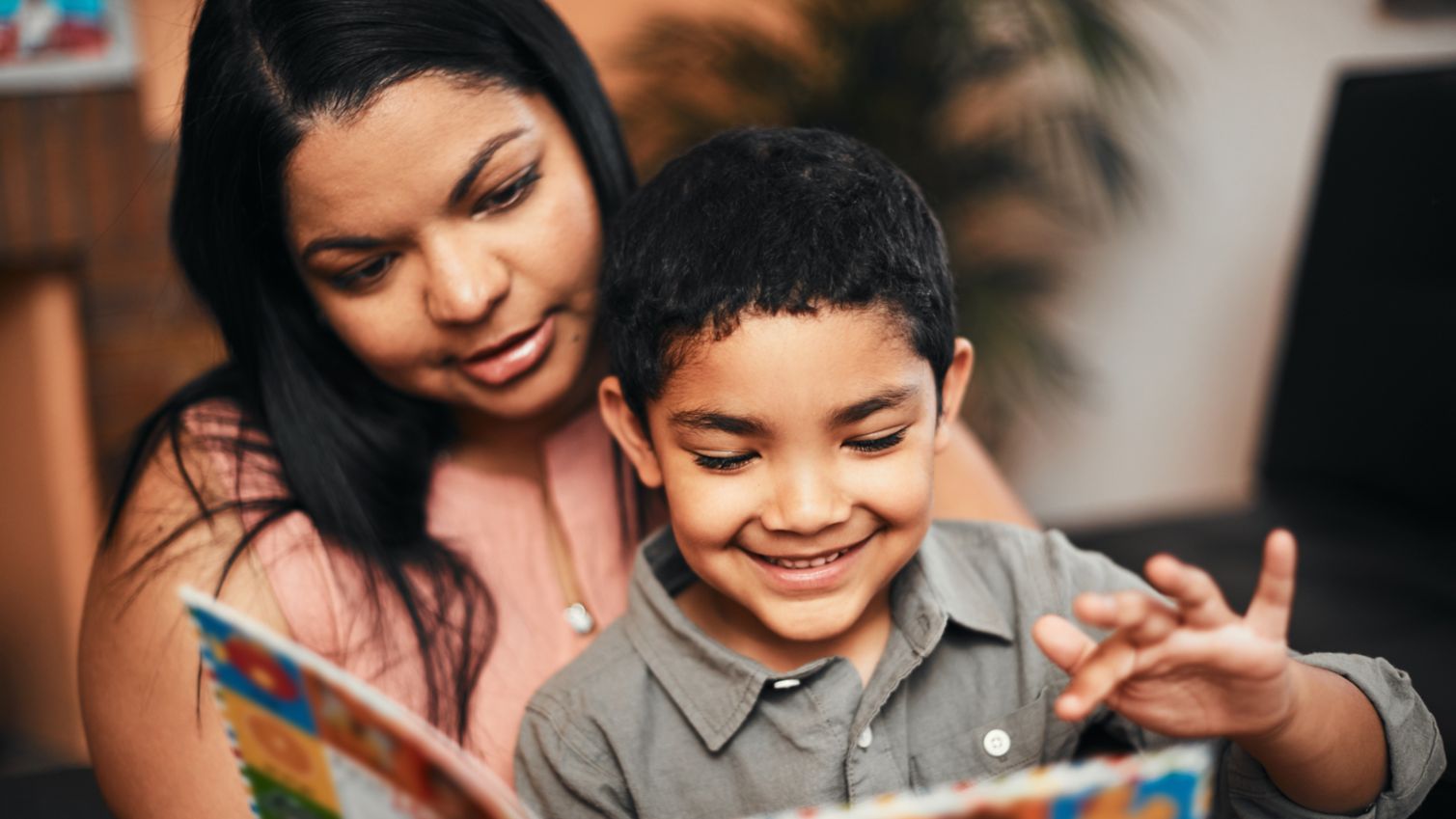 Mom holds son while they read a book