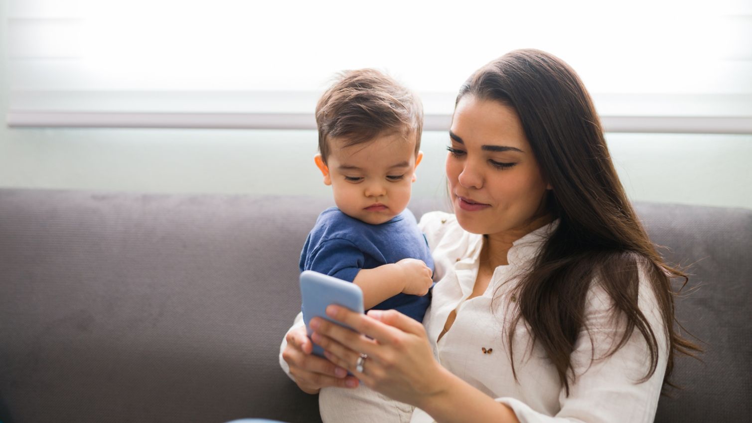 young mother holding child and looking at phone