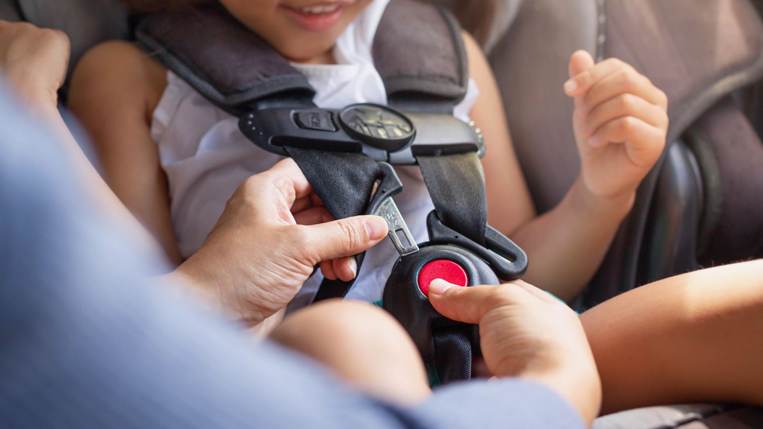 Parent buckles daughter into car seat