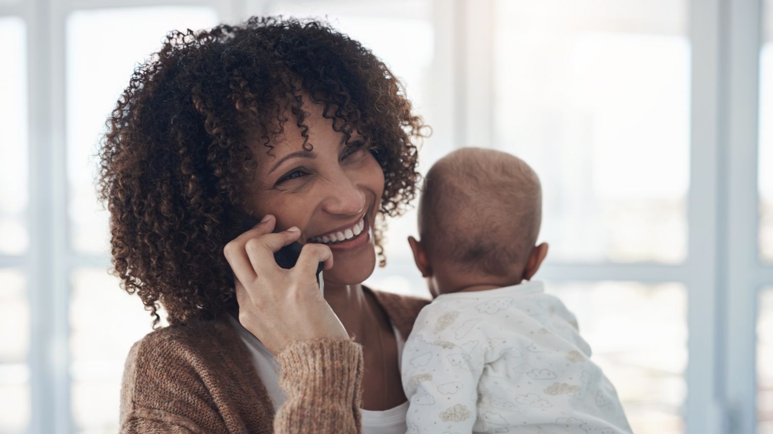 Medicaid member holding baby and talking on the phone.