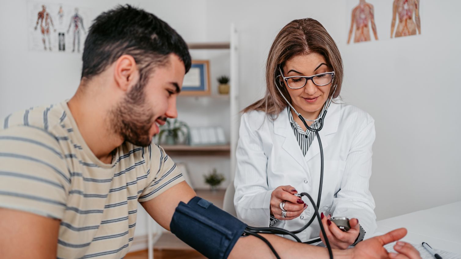 Doctor taking blood pressure of young male patient.