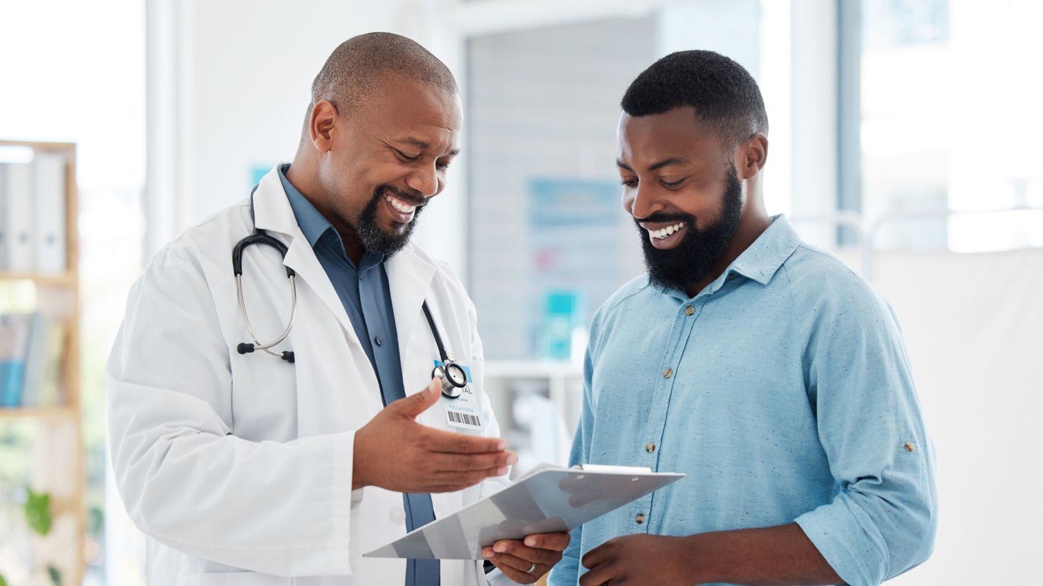 A physician laughs with a patient while reviewing their chart