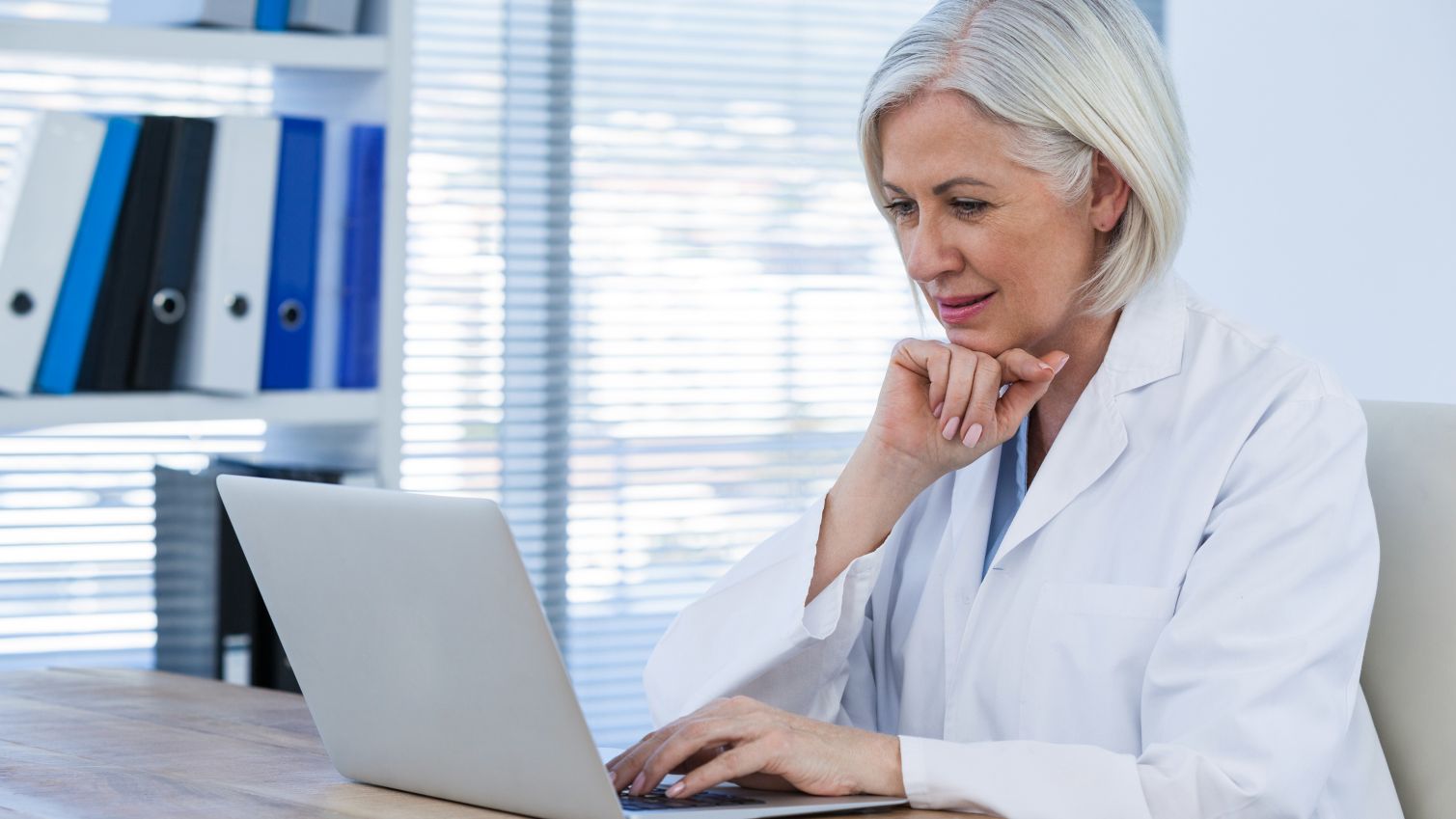 A female physician thinks deeply while reading information on her laptop