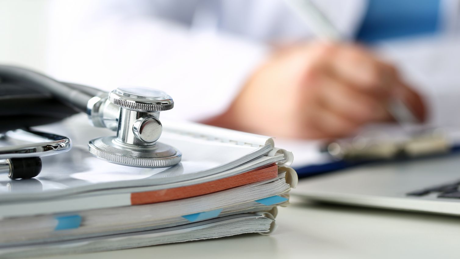 A closeup of a stethoscope on a stack of notebooks