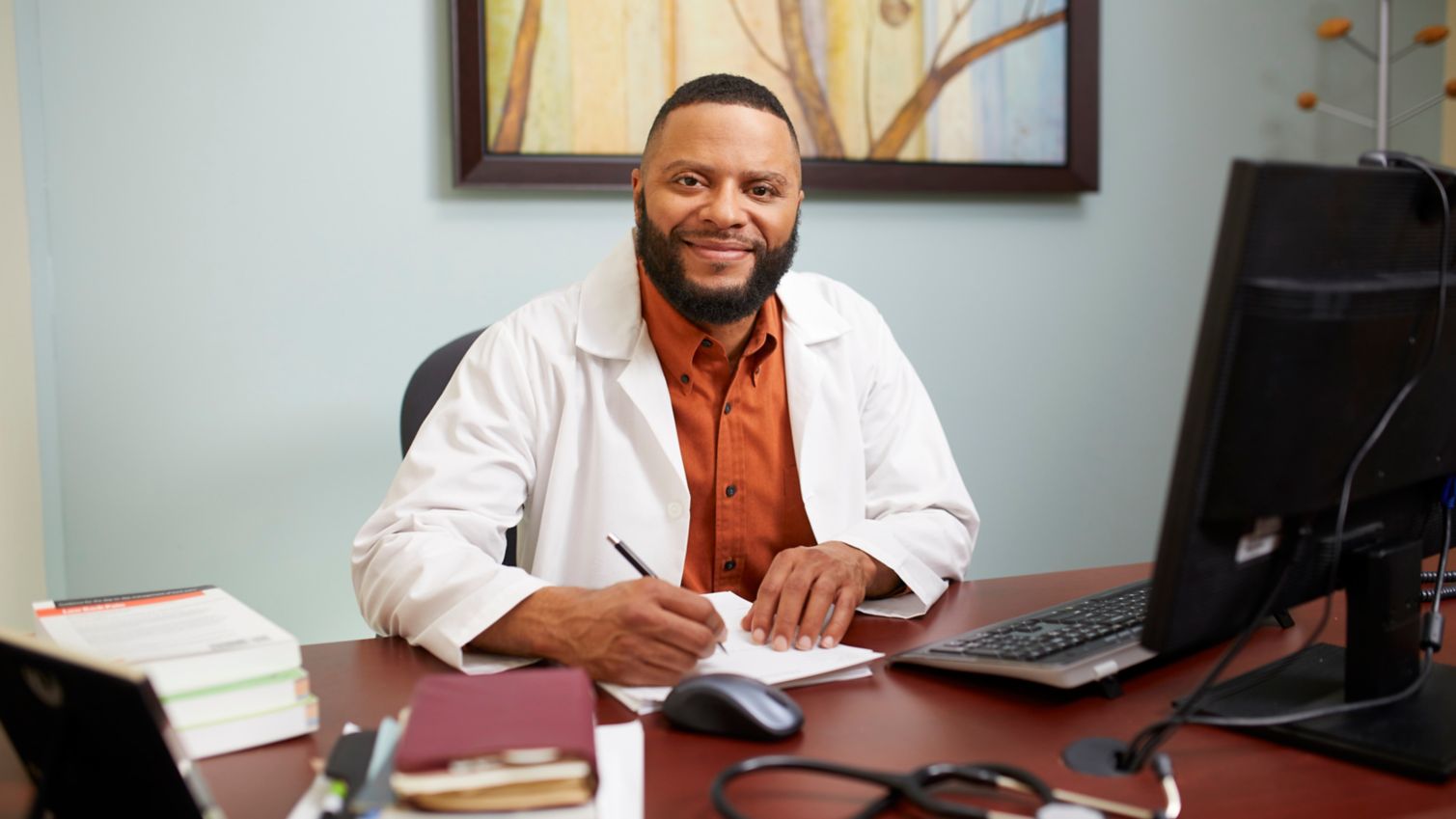 A provider sits at his computer and smiles at the camera