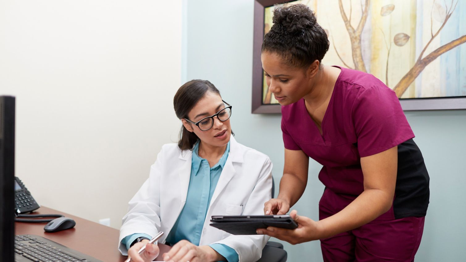 A dental assistant consults with a dentist about a patient