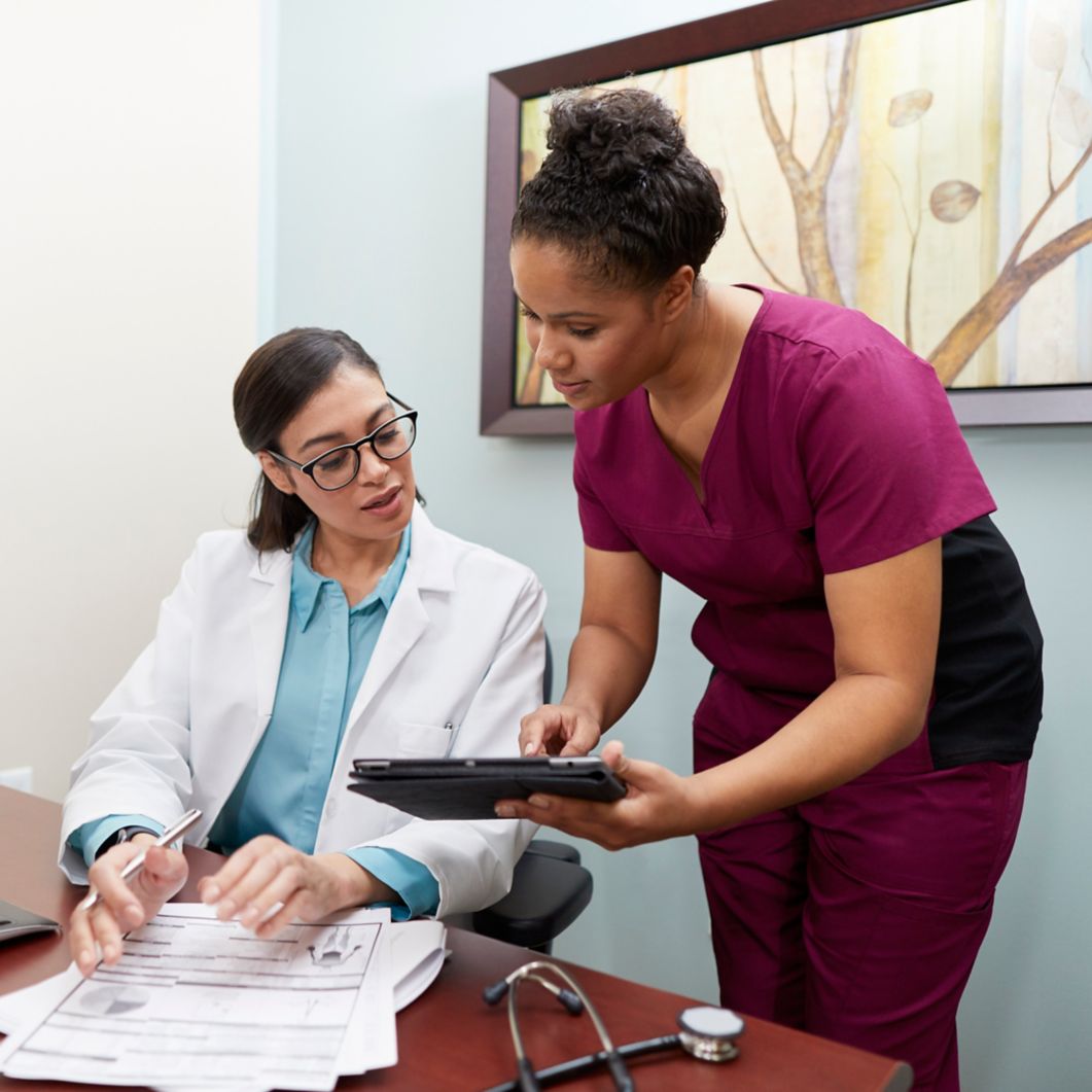 A dental assistant consults with a dentist about a patient