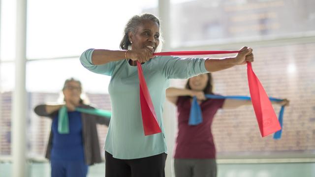 Older woman exercises with resistance bands.
