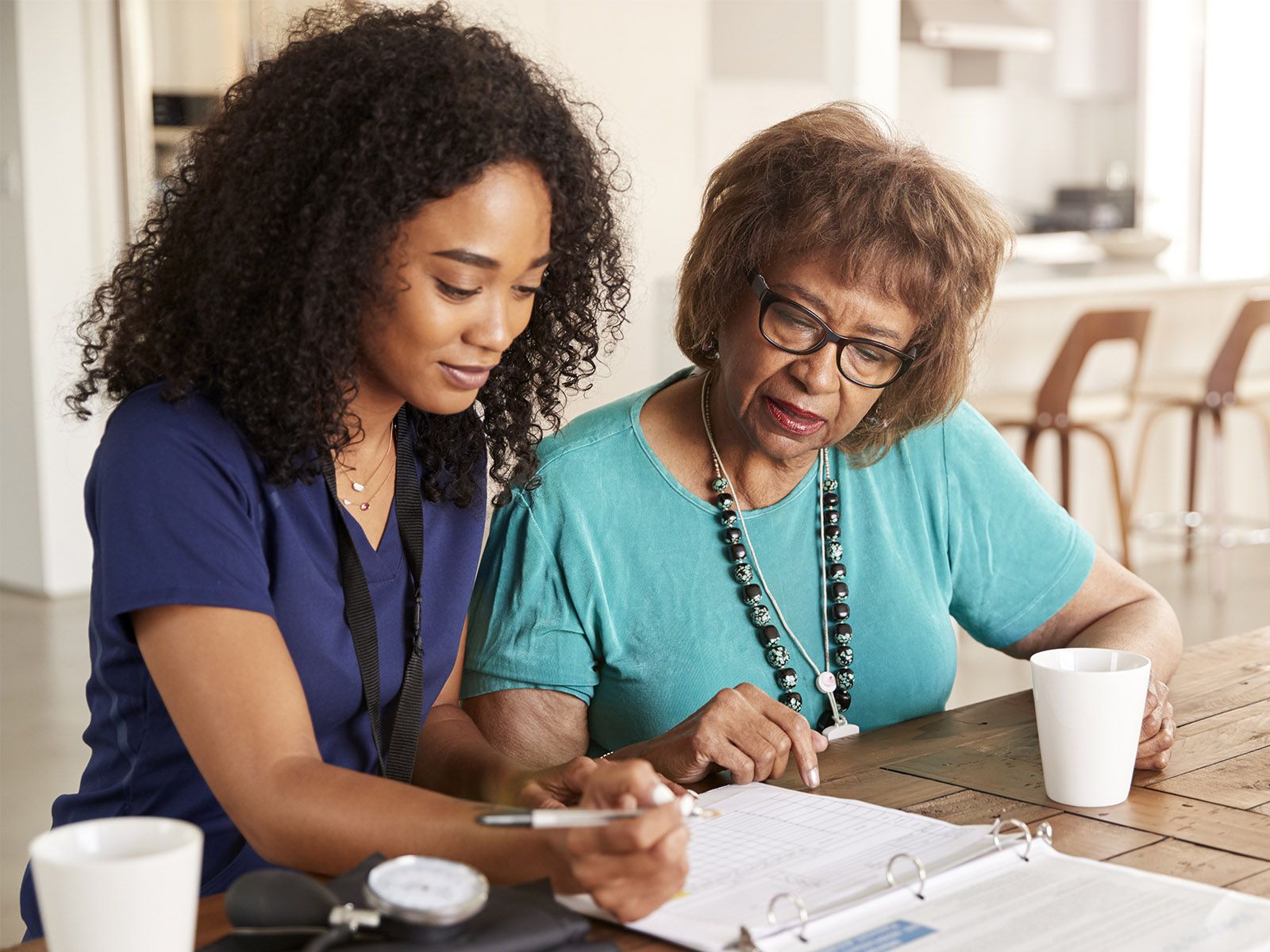 A home health aide gets ready to prepare a meal in a woman's kitchen.