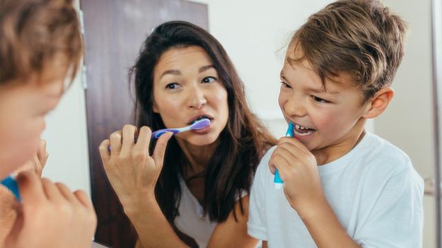 Mother teaching her kid teeth brushing.